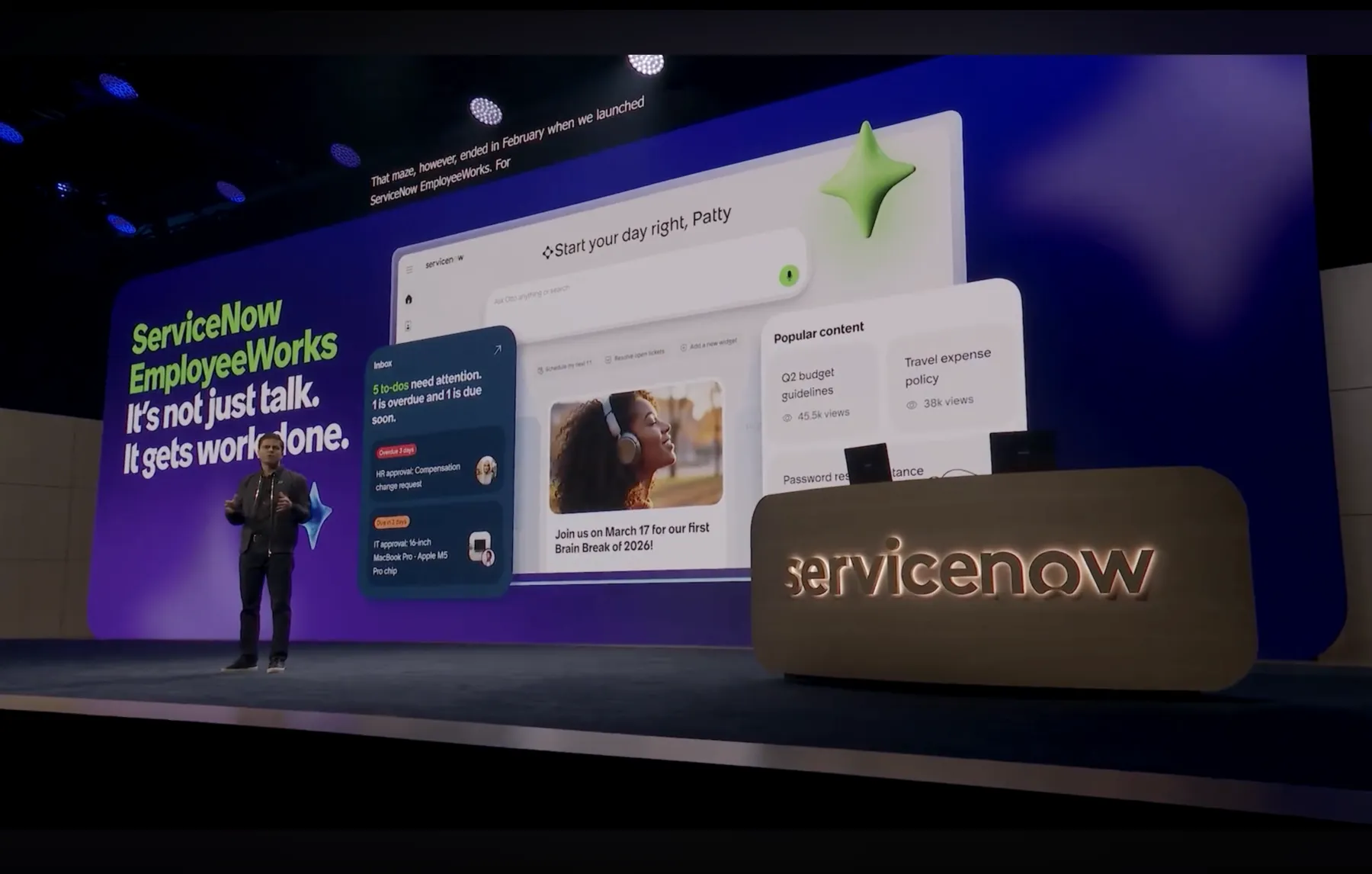 ServiceNow EmployeeWorks on stage at Knowledge 2026, with the tagline 'It's not just talk. It gets work done.' and the EmployeeWorks interface on screen behind the presenter.